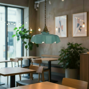 Teal pendant light hanging in a modern cafe with tables, chairs, and plants.