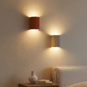 Two wall-mounted lamps casting light on a textured wall with a small table and decorative items below.