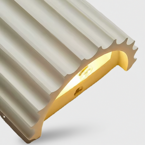 Close-up of a metallic architectural element with a ribbed surface on a light gray background