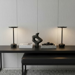 Modern interior with a black table, abstract sculpture, and decorative items against a light wall.