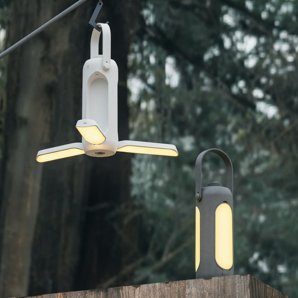 Two outdoor lights hanging on a wooden post with trees in the background