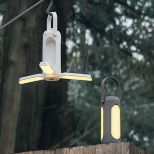 Two outdoor lights hanging on a wooden post with trees in the background