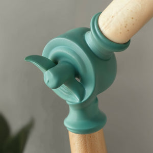 Teal bird-shaped kitchen tool handle on a wooden handle against a gray background