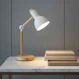 Wooden desk lamp on a marble surface with books and a box against a gray wall.