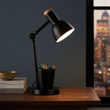Black desk lamp with a cup holder on a wooden surface, cityscape in the background