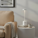 Modern lamp on a side table next to a beige armchair with a blanket