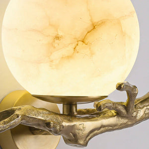 Decorative wall sconce with marble-like shade and gold metal base on a gray background
