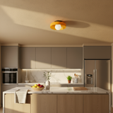 Modern kitchen with neutral tones, including a refrigerator, oven, and countertop with a bowl of fruit.