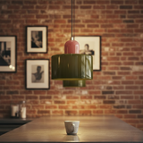 Green pendant light hanging above a wooden table with a brick wall background