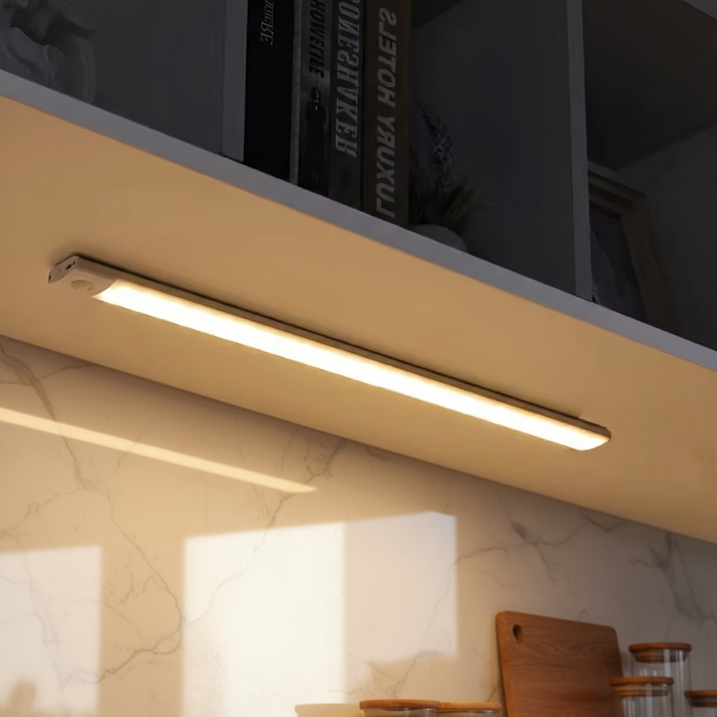 Under-cabinet light fixture in a kitchen setting with books on a shelf.
