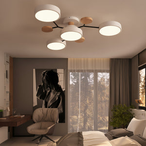 Modern ceiling light fixture in a bedroom with large windows and a view of trees.