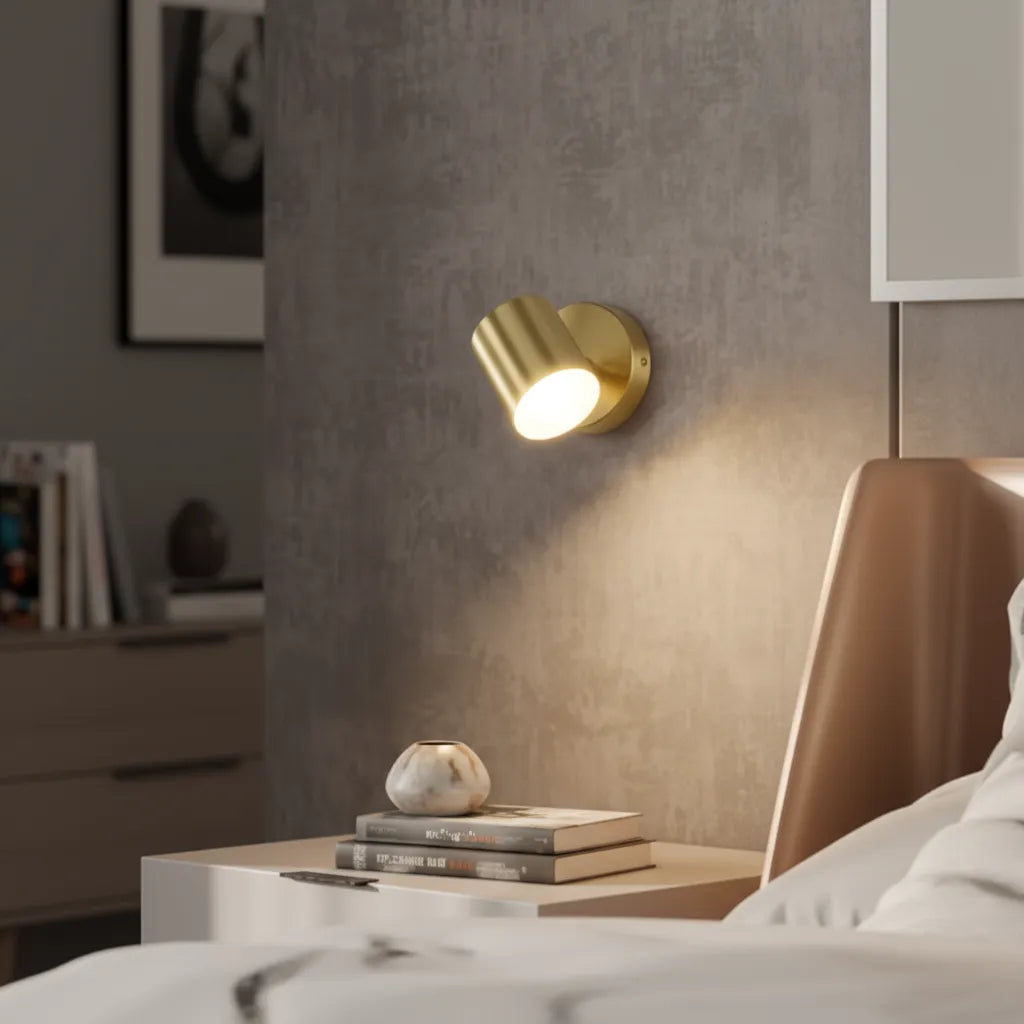 Gold wall sconce on a textured wall with books and a decorative object on a surface below.