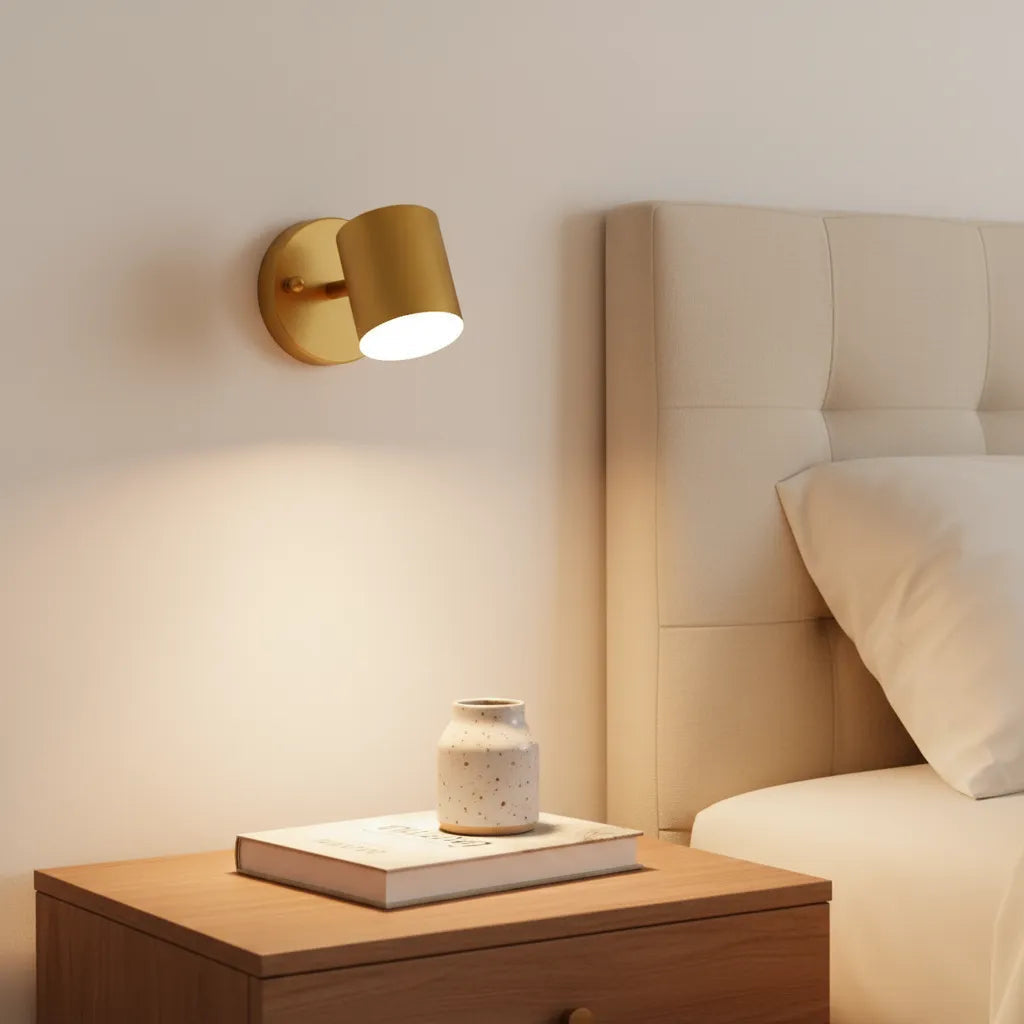 Gold wall sconce on a nightstand next to a bed with a headboard
