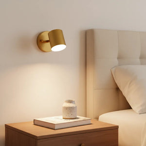 Gold wall sconce on a nightstand next to a bed with a headboard