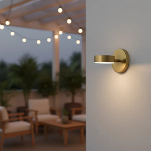 Gold outdoor wall light fixture on a patio with string lights in the background