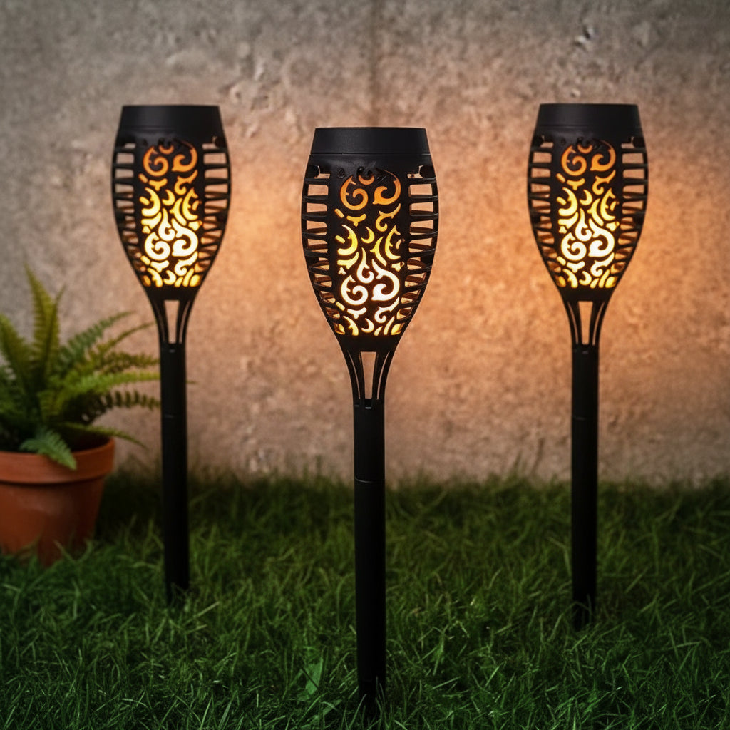 Three decorative garden lights with intricate designs on a grassy background
